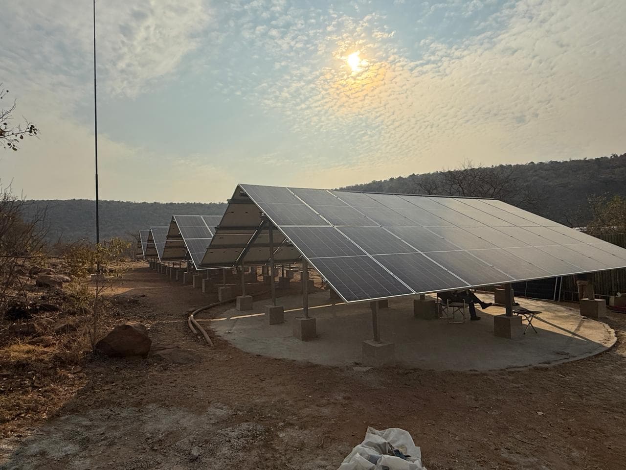 Ground-mounted solar array in the bushveld with the sun behind the panels